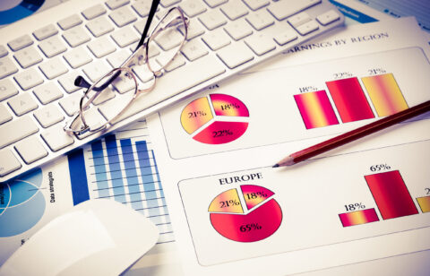 Business workplace with keyboard glasses and financial documents on table